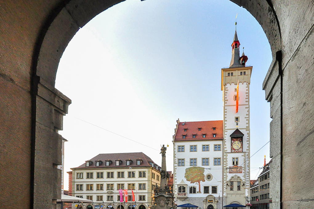 Der Grafeneckart und Vierröhrenbrunnen an der Alten Mainbrücke - Blick durch den Torbogen auf belebte Gassen. Foto: ©CTW Björn Rudek Der Grafeneckart und Vierröhrenbrunnen an der Alten Mainbrücke - Blick durch den Torbogen auf belebte Gassen. Foto: ©CTW Björn Rudek